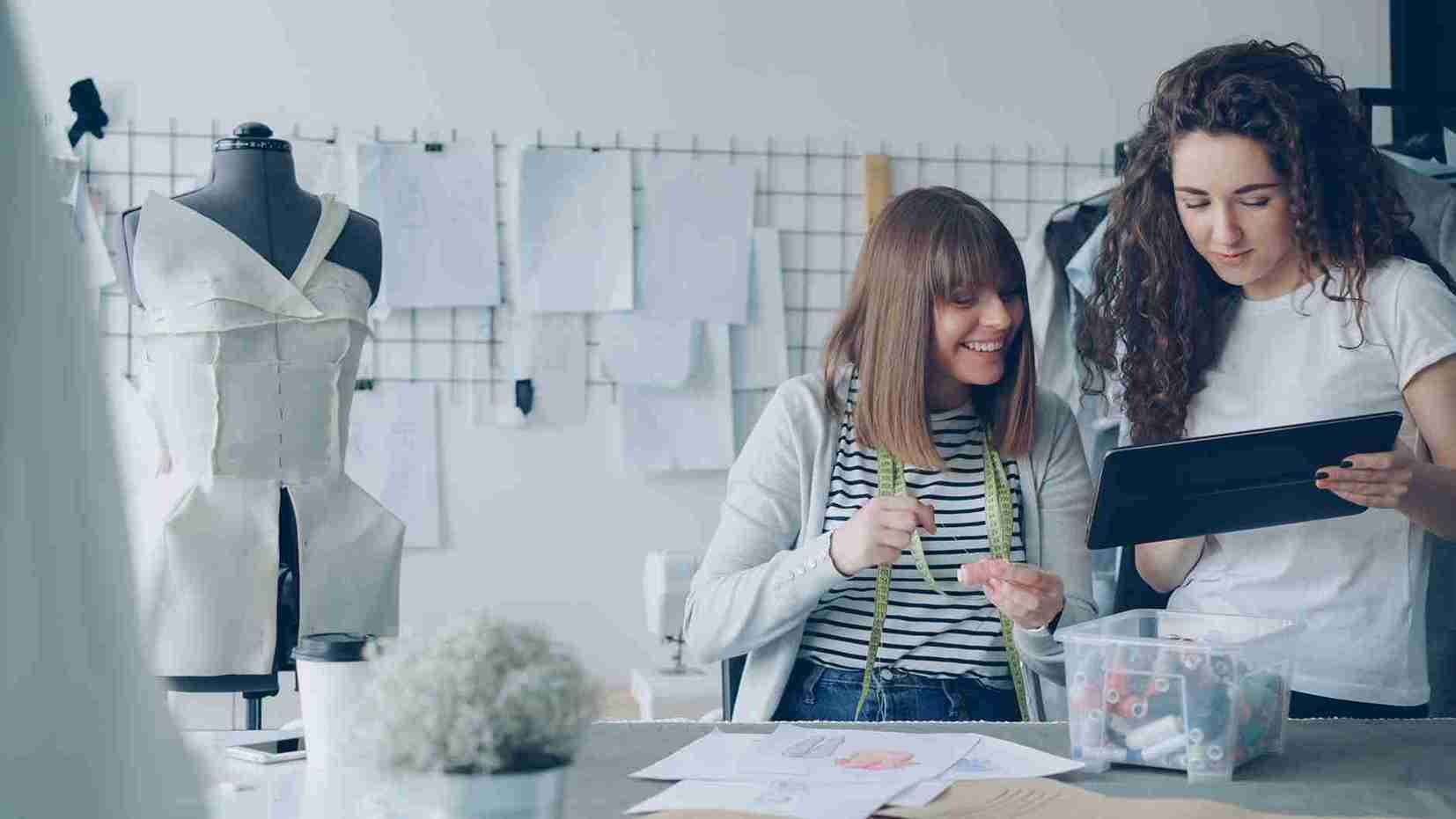 Fashion curator reviewing fabric swatches beside a clothing rack